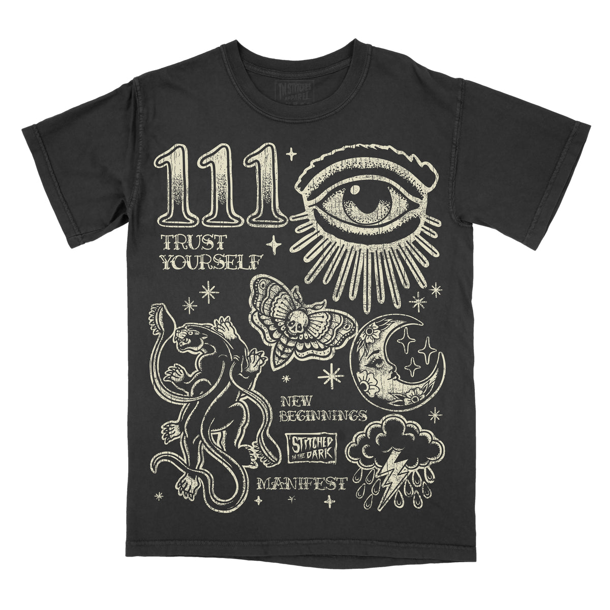 black T-shirt featuring a distressed 111 angel number design with an all-seeing eye, black panther, moth, moon, stars, and storm cloud, with text reading “Trust Yourself,” “New Beginnings,” and “Manifest,” plus Stitched in the Dark branding.