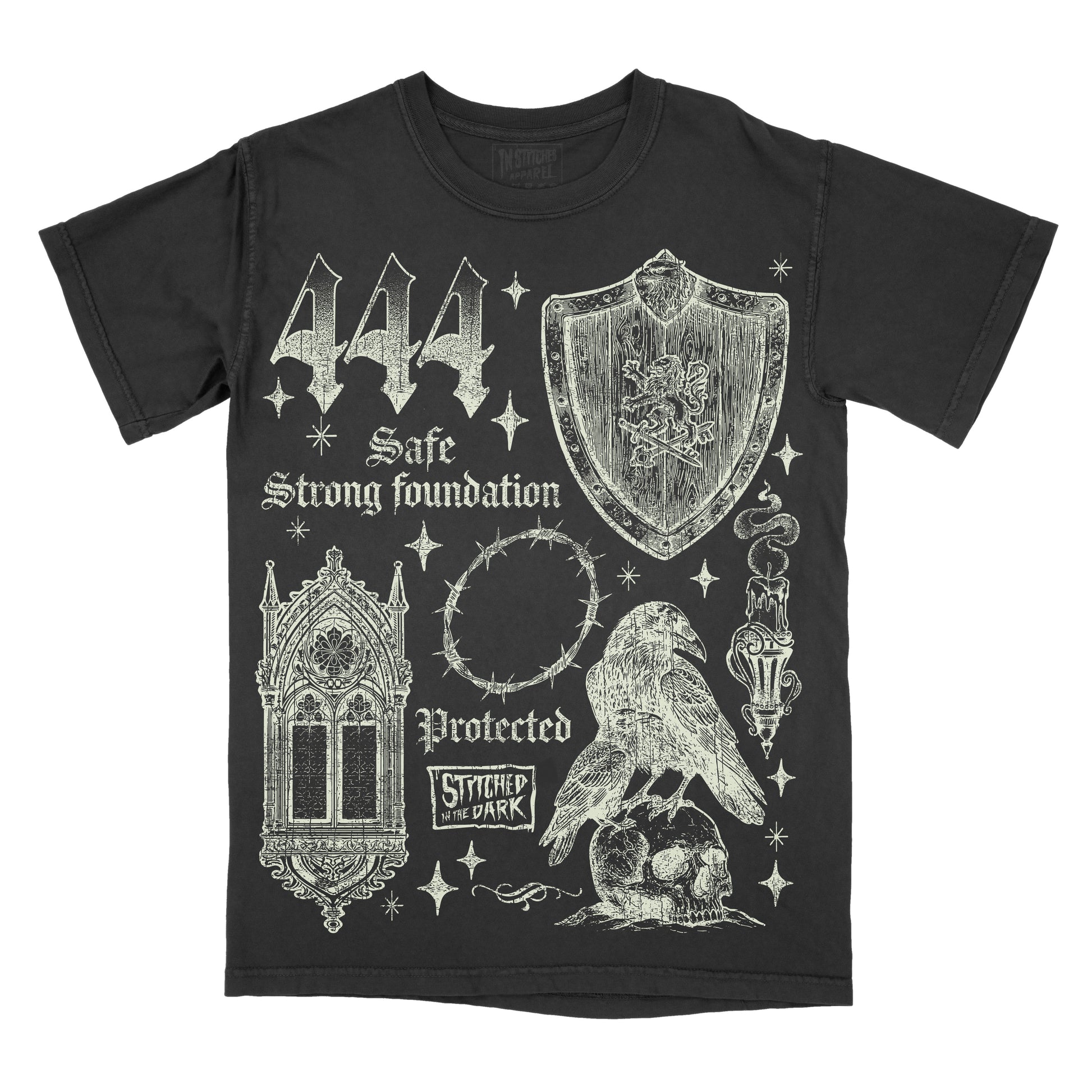 black T-shirt featuring a distressed 444 angel number design with a medieval shield, gothic window, barbed wire halo, raven perched on a skull, and candle, with text reading “Safe,” “Strong Foundation,” and “Protected,” plus Stitched in the Dark branding.
