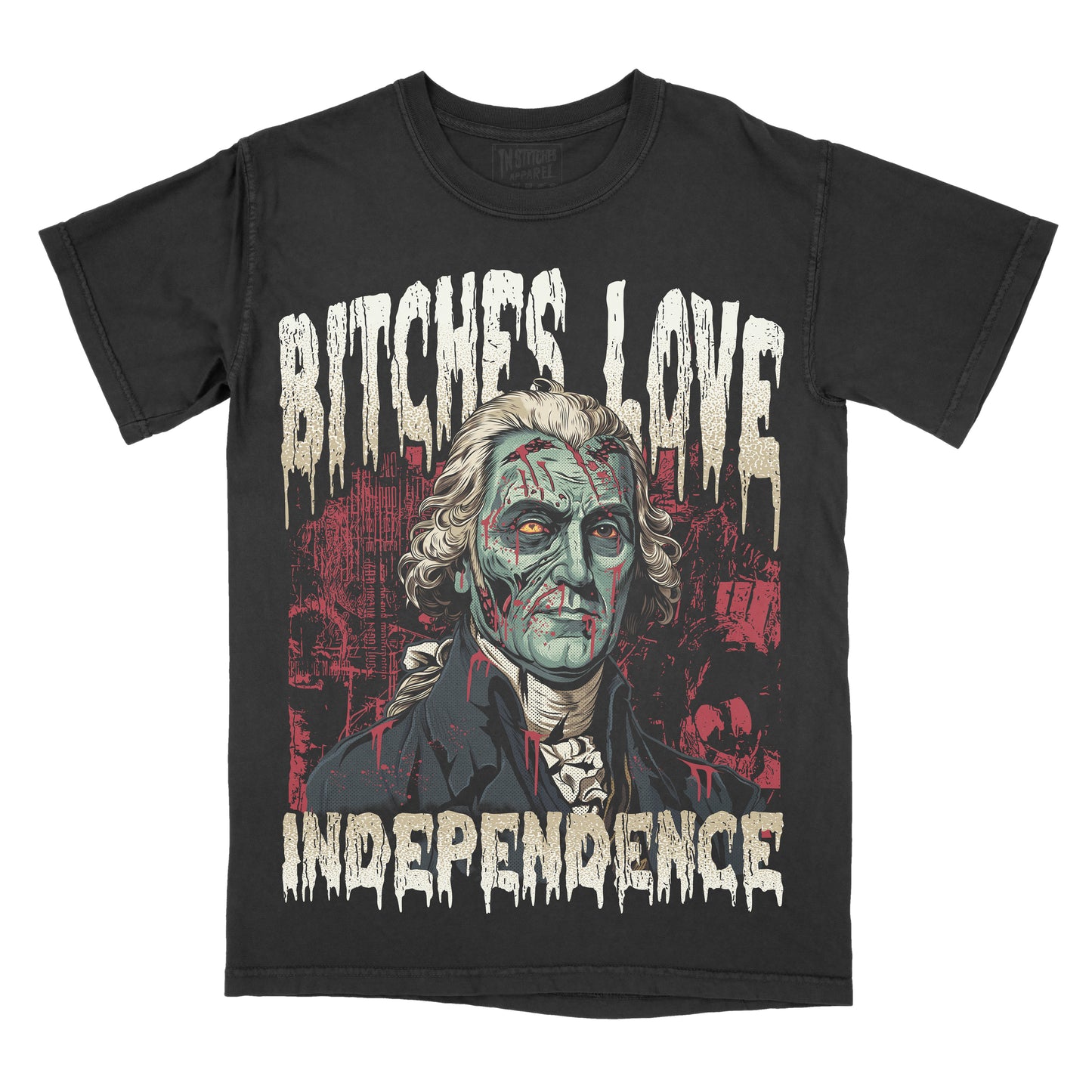 A black short-sleeve graphic t-shirt featuring a distressed print of George Washington with zombie-like green skin, the text 'BITCHES LOVE INDEPENDENCE' in a dripping white font, and a red cityscape background.