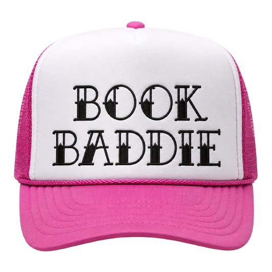 Pink and white foam trucker hat with black embroidered “Book Baddie” design, pink mesh back, pink rope detail, and curved pink bill.