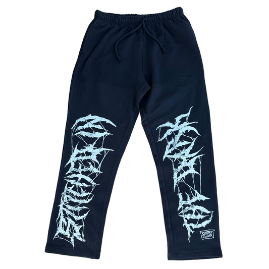 Black straight-leg sweatpants with an elastic drawstring waist featuring distressed white “Stitched in the Dark” lettering in a metal-style font printed vertically down both legs.
