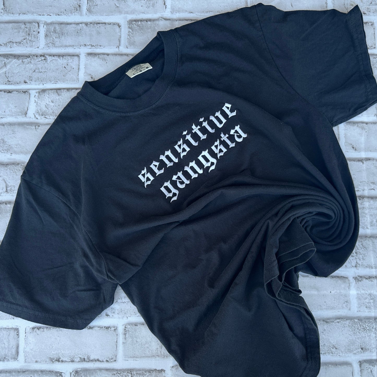 Black Comfort Colors T-shirt featuring white embroidered Old English text across the chest that reads “Sensitive Gangsta.”