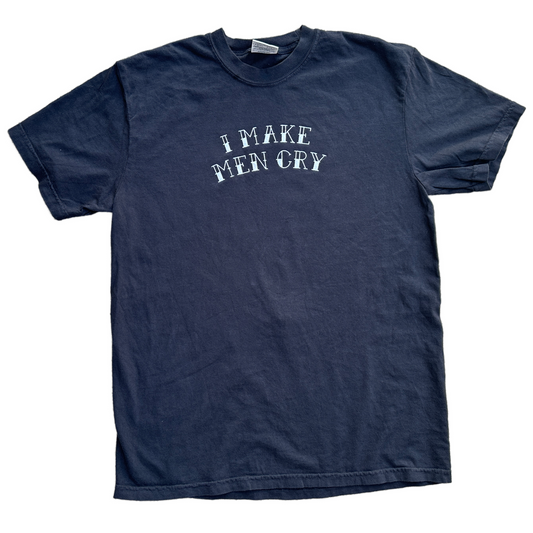 A black short-sleeve t-shirt with the phrase 'I MAKE MEN CRY' embroidered in a distressed white font across the chest, laid flat against a white background.