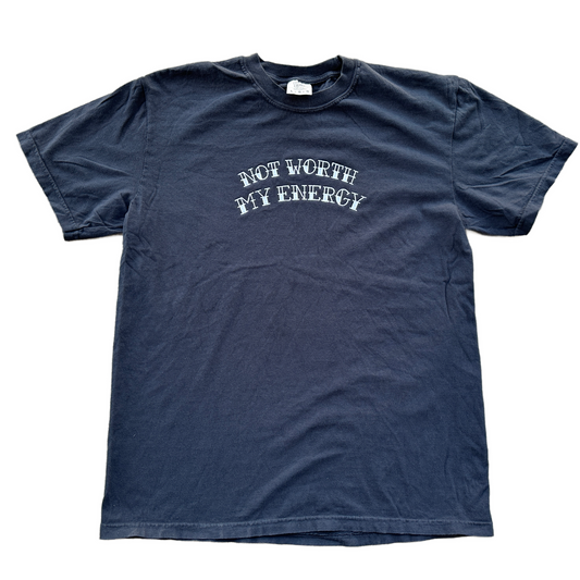 A black short-sleeve t-shirt with the phrase 'NOT WORTH MY ENERGY' embroidered in white arched text across the chest, laid flat on a white background.