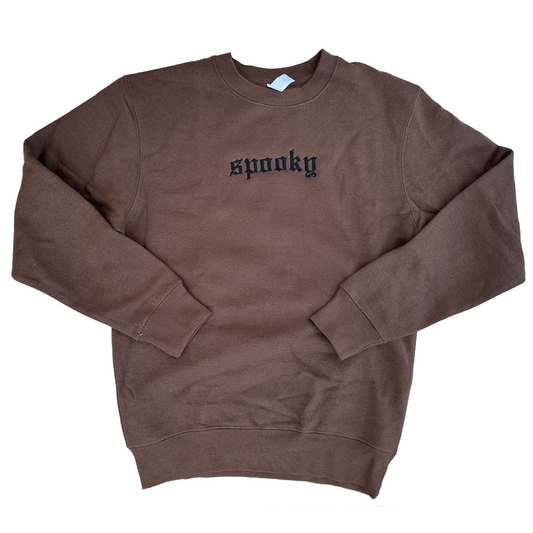 Brown crewneck sweatshirt featuring black embroidered Old English text across the chest that reads “spooky,” shown on a white background.