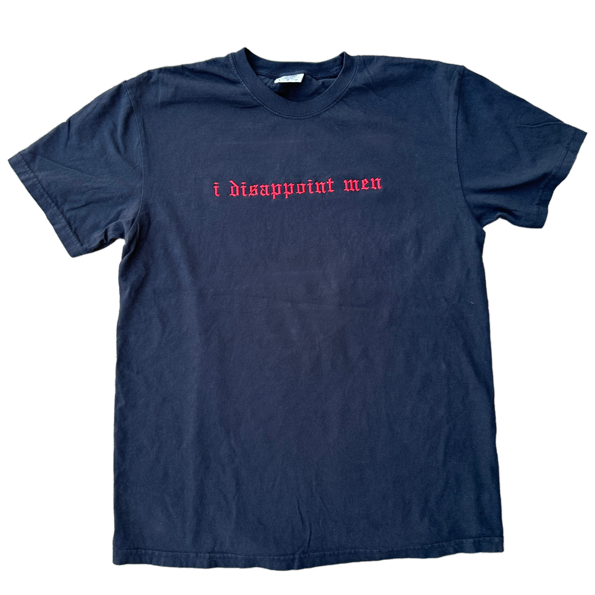 A black short-sleeve t-shirt with the phrase 'i disappoint men' embroidered across the chest in a red gothic font, laid flat against a white background.