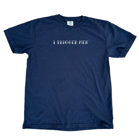 A black short-sleeve crewneck t-shirt with the text 'I TRIGGER MEN' embroidered in white across the chest, displayed flat against a white background.