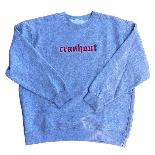 A heather gray crewneck sweatshirt with the word 'crashout' embroidered in red Gothic-style lettering across the chest, displayed flat against a white background.