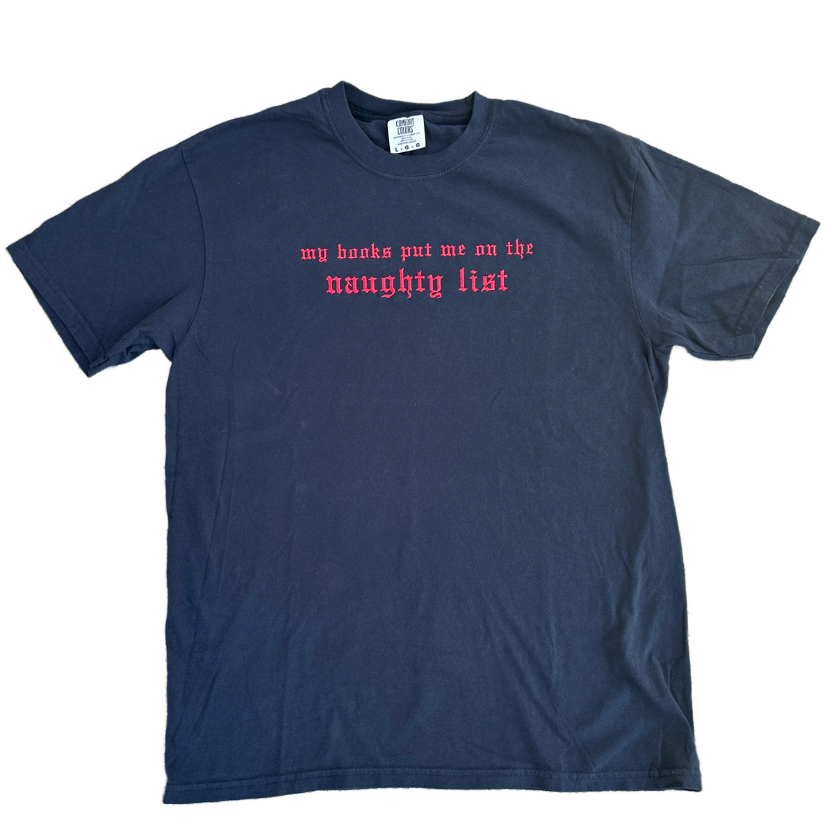 Black Comfort Colors T-shirt featuring bright red embroidered Old English text across the chest that reads “my books put me on the naughty list.
