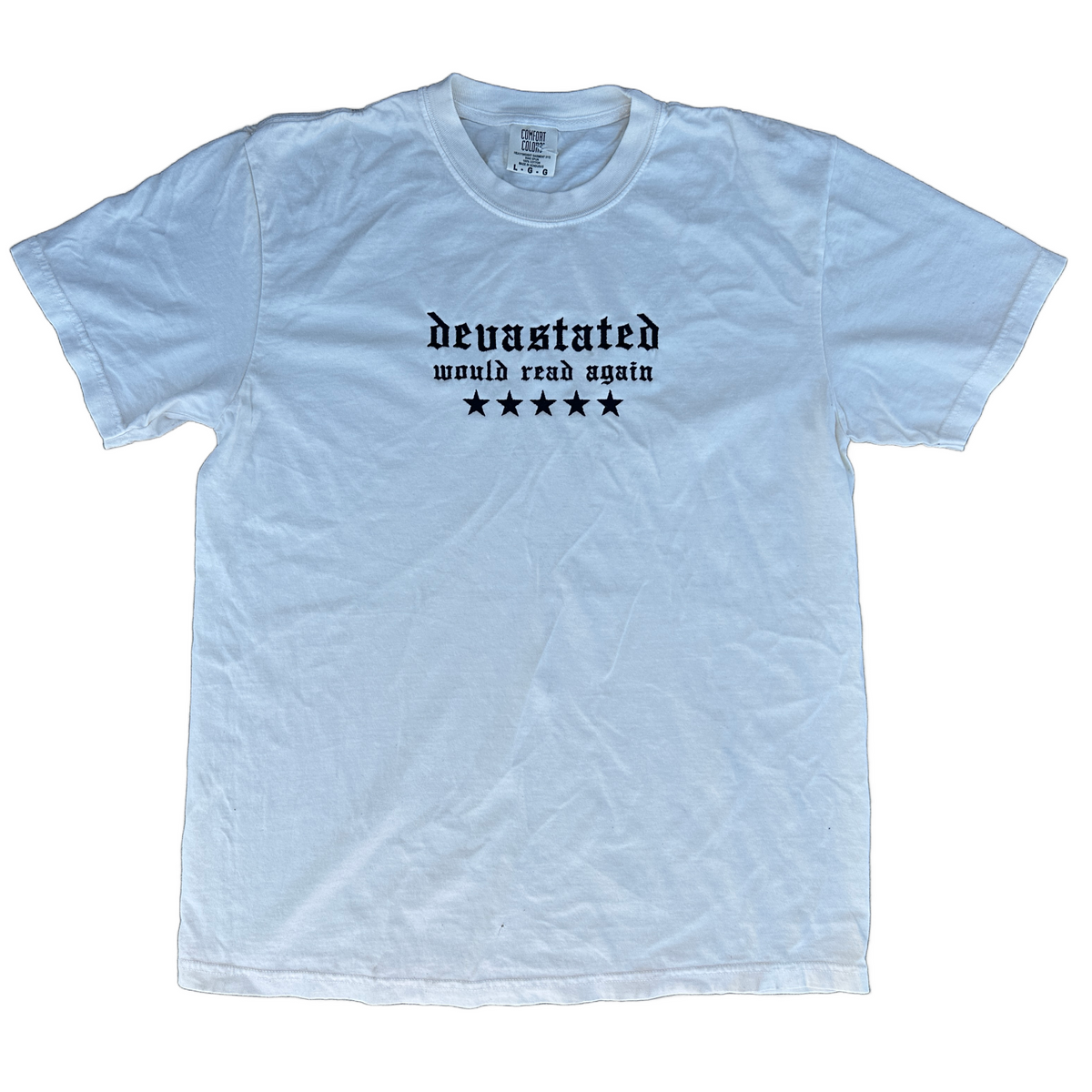Comfort Colors T-shirt featuring black Old English embroidered text reading “devastated” with “would read again” underneath and five black stars across the chest.