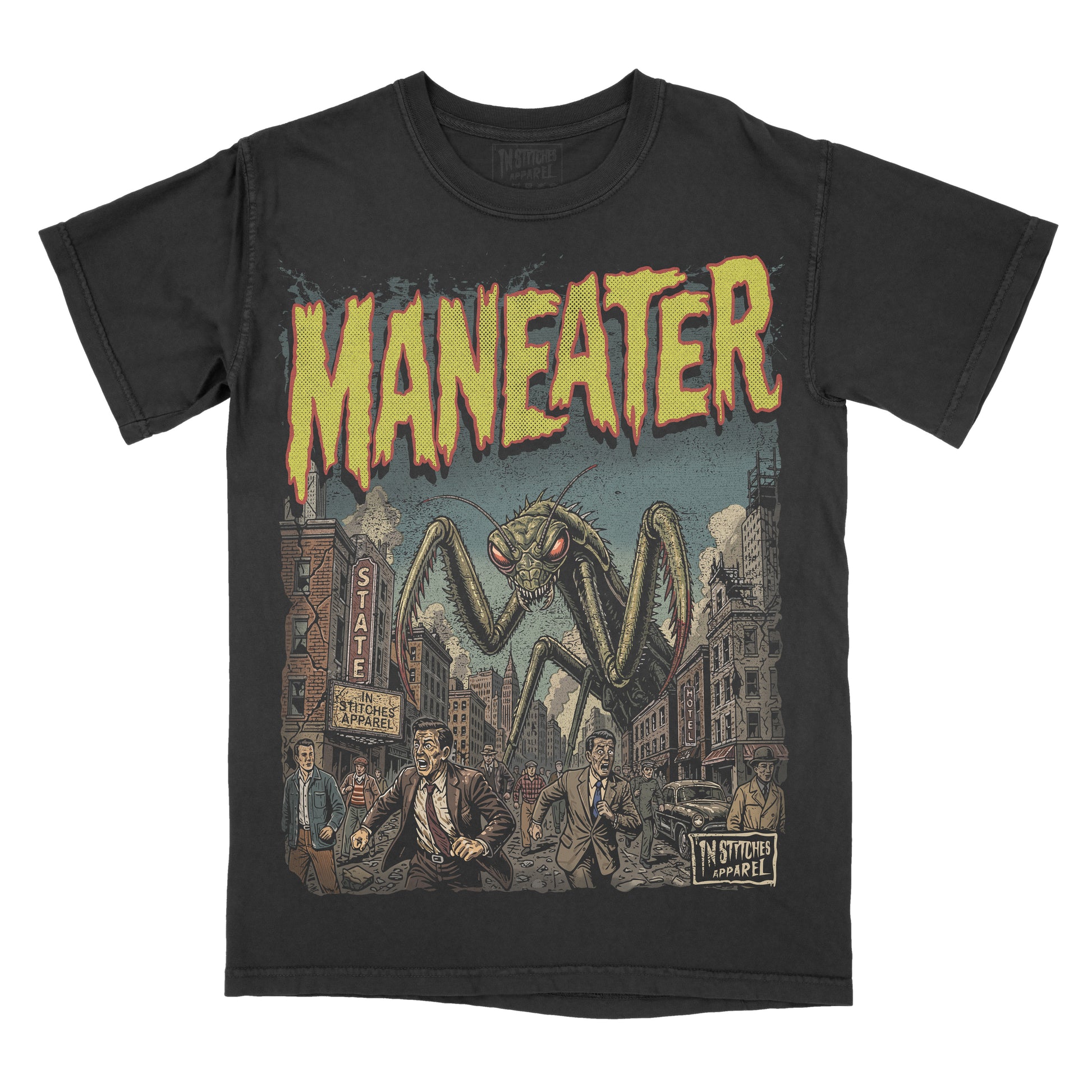 A black short-sleeve graphic t-shirt featuring a vintage-style illustration of a giant praying mantis in a city street under the word 'MANEATER' in yellow dripping letters, with 'IN STITCHES APPAREL' printed on the lower right of the graphic.