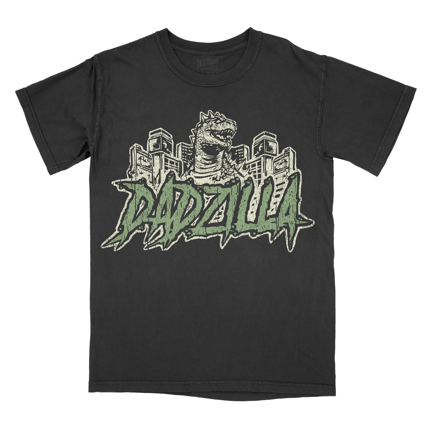 Black vintage-wash graphic T-shirt featuring a retro Godzilla-inspired monster towering over a city skyline above bold green graffiti-style lettering that reads "DADZILLA."