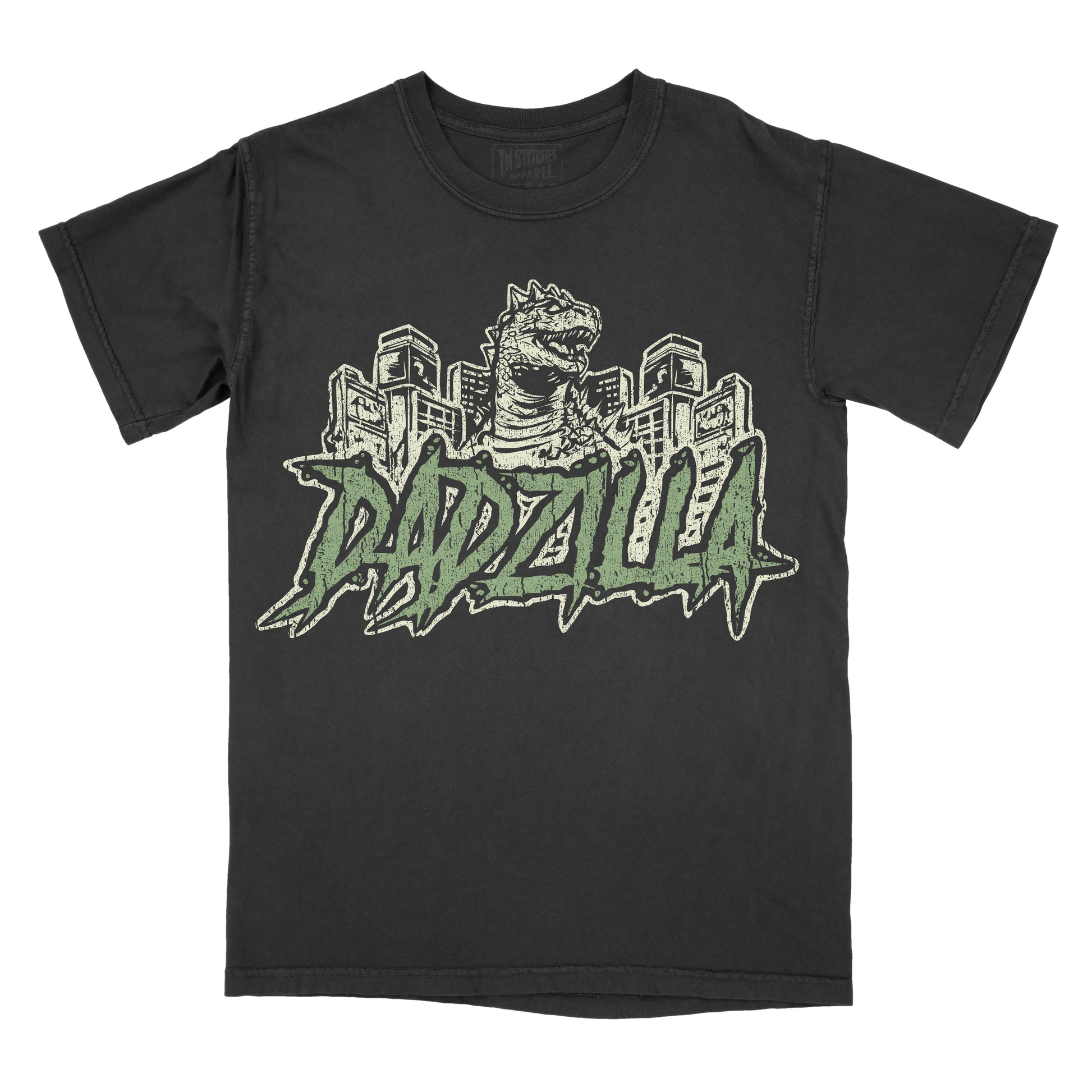 Black vintage-wash graphic T-shirt featuring a retro Godzilla-inspired monster towering over a city skyline above bold green graffiti-style lettering that reads "DADZILLA."