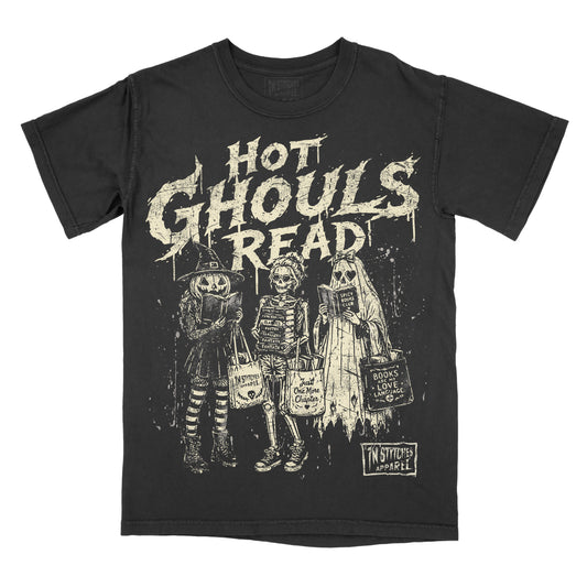 A black short-sleeve graphic t-shirt featuring the distressed white text 'HOT GHOULS READ' above three skeleton characters in Halloween costumes holding bags, with a 'In Stitches Apparel' logo in the bottom right corner.
