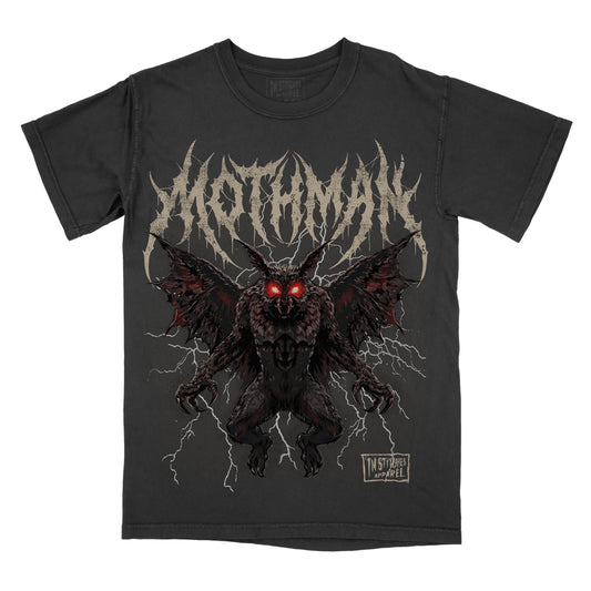 A black short-sleeve graphic t-shirt featuring the name 'Mothman' in a jagged off-white font above a detailed illustration of a dark, winged creature with glowing red eyes and lightning effects. A small 'In Stitches Apparel' logo is visible on the bottom right of the graphic.