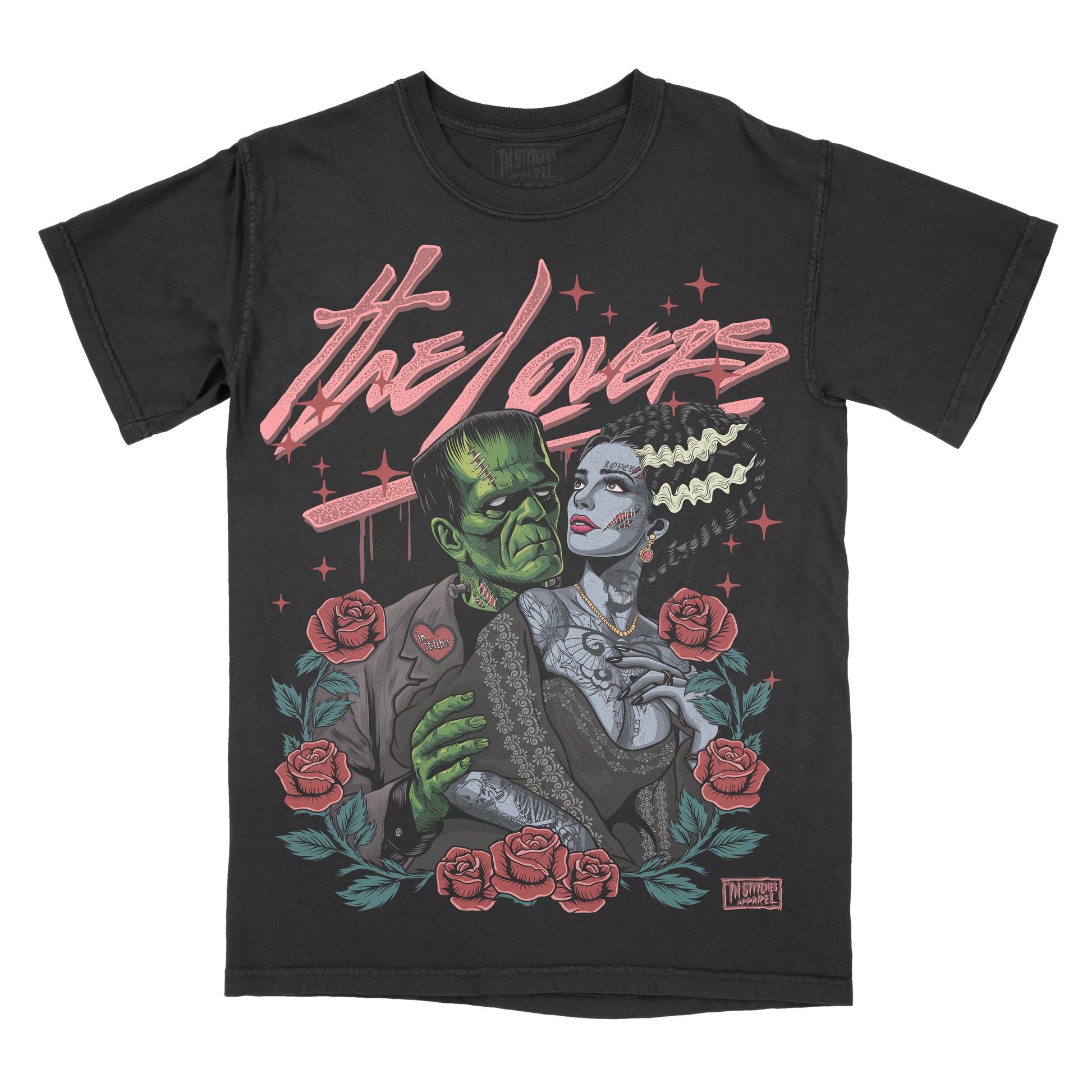 A black short-sleeve graphic t-shirt featuring a retro-style illustration of Frankenstein and The Bride under the text 'the lovers' in pink script, surrounded by red roses and green leaves.